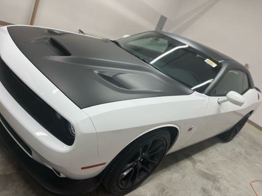 White Dodge Challenger with a dark hood and tinted windows