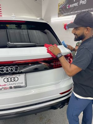 Technician applying film to the rear of a white Audi